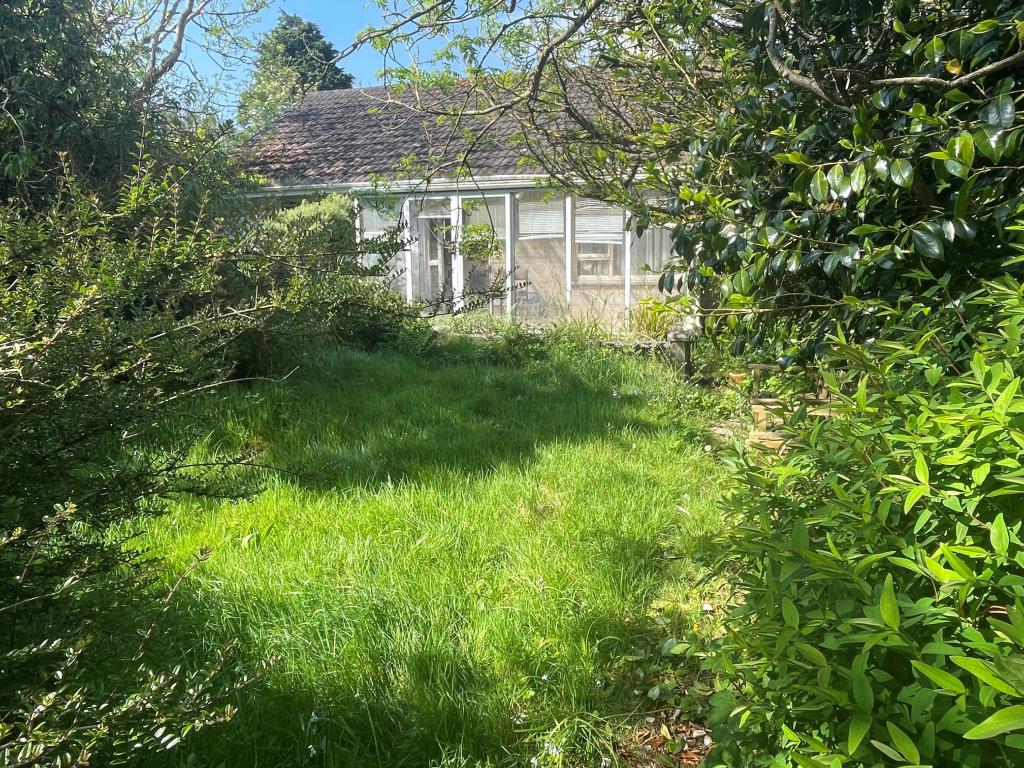 Lot: 147 - DETACHED BUNGALOW WITH POTENTIAL AND FAR REACHING VIEWS - Part of garden in fore ground with conservatory